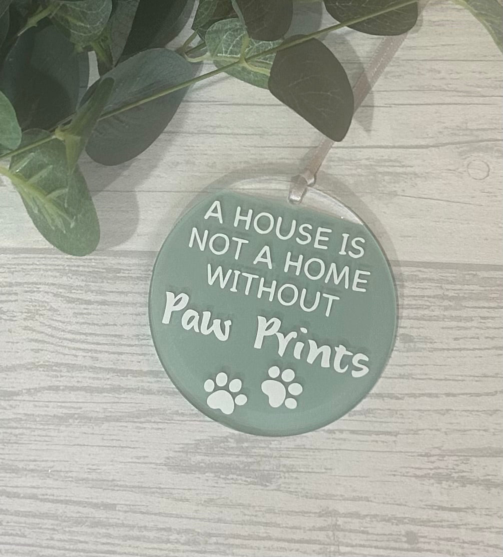 Round acrylic hanging decoration with white wording and paw print detail with sage acrylic paint and satin ribbon